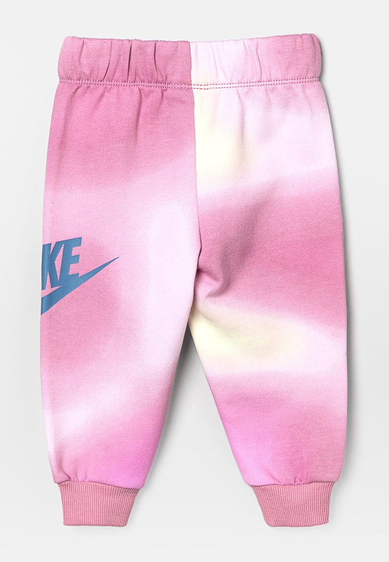Pantalons de survêtement rose clair avec un design dégradé et des accents jaune clair, et un logo Nike bleu sur la jambe gauche. Ceinture élastique en haut.