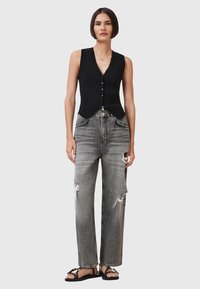 Zwarte geribbelde mouwloze top met een V-hals en knoopsluiting, gecombineerd met grijze verwerkte wide-leg jeans en zwarte platte sandalen.