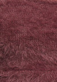 Tissu velouté bordeaux avec une surface texturée et duveteuse et un motif tissé, présentant des longueurs de fil variées pour plus de détails.