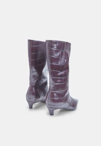 Knee-high, sügavale burgundias valged saapad, mis on valmistatud läikivast krokodillimustriga materjalist, terava varbaga ja madala kontsaga. Külgedel on peen metalline aksessuaar.