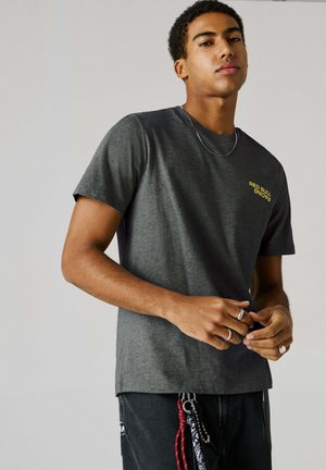Grå kortærmet t-shirt med rund hals, med gul "RED BULL RACING" tekst på venstre bryst, lavet af blødt stof.