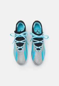 Zapatillas deportivas con un diseño en plata y negro con detalles en azul, parte superior de tejido, cordones planos y detalles perforados en la puntera.