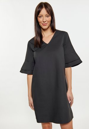 Zwarte jurk met een V-hals en uitlopende korte mouwen, gemaakt van gladde stof; kniehoogte met een losse pasvorm. Minimalistisch ontwerp zonder patronen.
