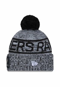 Gestrickte Beanie in Grau mit schwarzen Akzenten, ausgestattet mit einem großen schwarzen Bommel oben und "RAIDERS"-Schriftzug am Rand. Weißes Logo-Patch sichtbar.