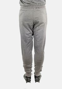 Graue sportliche Jogginghosen mit elastischem Taillenbund, gerippten Bündchen und seitlichen Taschen, kombiniert mit schwarzen Sportschuhen. Enganliegendes Design von der Rückansicht.