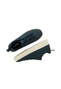 Tmavě modré semišové tenisky s bílou podrážkou, které mají šněrování, poutko na patě a texturované detaily na povrchu.