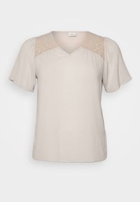 Blusa beige a maniche corte con scollo a V e dettagli in pizzo sulle spalle, con maniche ampie in stile svolazzante e un tessuto testurizzato.