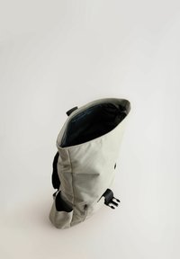 Sac à dos en tissu gris avec une ouverture supérieure, accents noirs, poche latérale et doublure intérieure à motifs. Dispose de bretelles réglables.