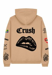 Felpa beige con una grande grafica di labbra nere e il testo "Crush". Presenta toppe colorate e testo sulle maniche, polsini a costine e orlo.