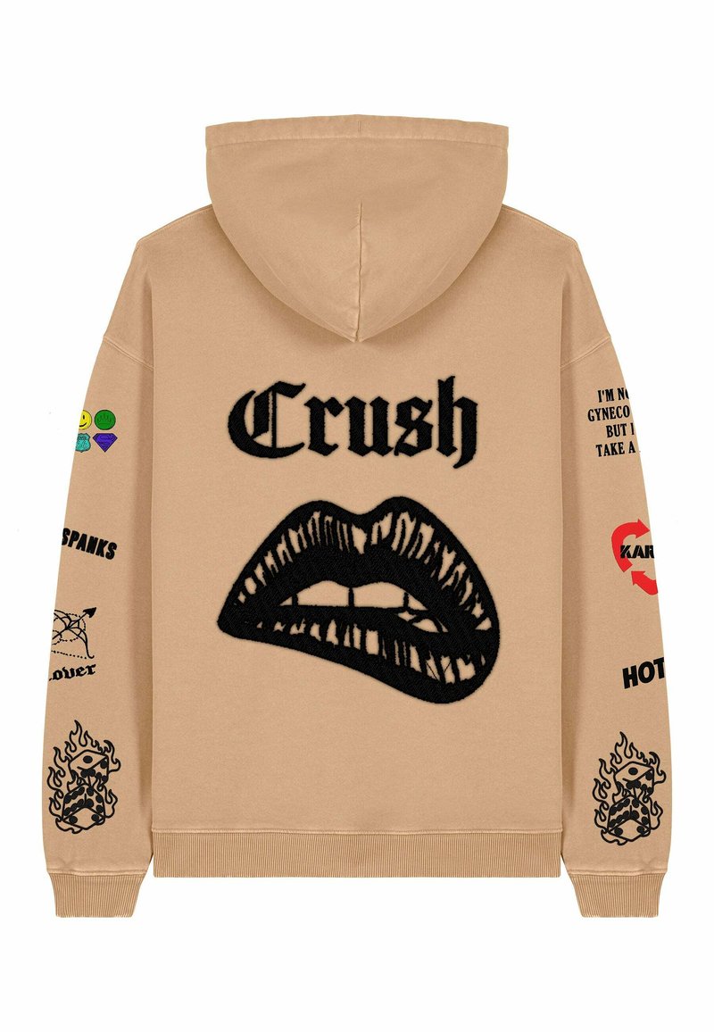 Felpa beige con una grande grafica di labbra nere e il testo "Crush". Presenta toppe colorate e testo sulle maniche, polsini a costine e orlo.