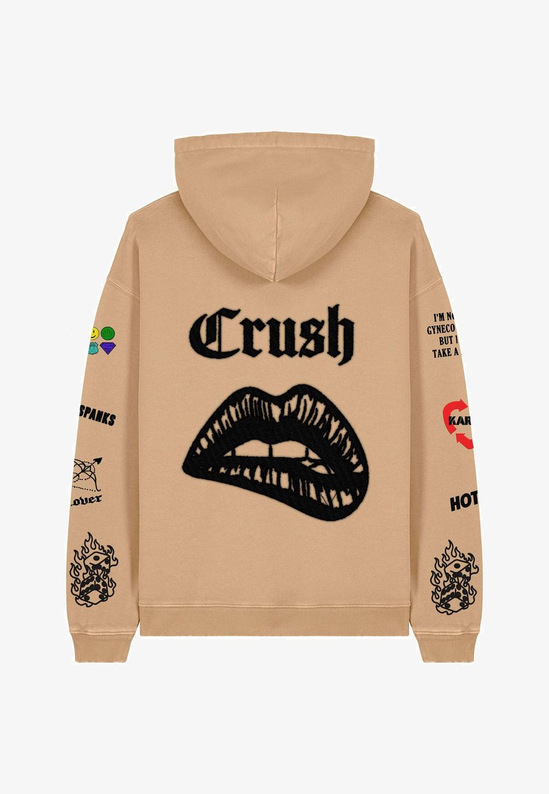 Beige hoodie with a large black lip graphic and "Crush" text. Features colorful patches and text on sleeves, ribbed cuffs, and hem.