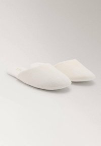 Par brezbarvnih, zaprtih fabric čevljev z minimalisticnim dizajnom, prikazanih na svetli nevtralni površini.