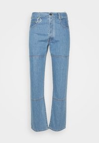 Světle modré džínové kalhoty mají rovný střih, přední kapsy a detail švů. Na pasu je kovový kruhový detail.