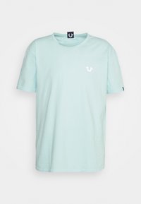 Světle modré bavlněné tričko s krátkými rukávy, kulatým výstřihem a malým bílým logem na levé straně hrudi. Jednoduchý a rovný střih.