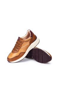 Zapatillas de cuero marrón con una suela media blanca, que presentan acentos en burdeos en contraste, diseño con cordones, costuras decorativas y suela de goma texturizada.