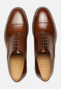 Scarpe da uomo in pelle marrone lucida, con punta arrotondata, chiusura con lacci e dettagli di cucitura sottili sulla parte superiore e sui lati.