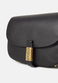 Geantă de mână din piele neagră, cu un capac rotunjit, un accent din hardware auriu cu inscripția "PINKO" și o textură netedă. Design minimalist.