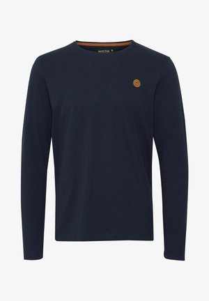 Marinblå långärmad skjorta i bomull med rund halsringning, kontrasterande inre halsband, och en liten brun logotyp patch på bröstet.