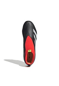 Zapatilla deportiva negra con un diseño elegante; presenta una parte superior de textil roja y tres franjas blancas; superficie texturizada; acento amarillo en el talón.