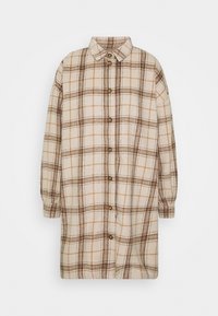 Abito camicia a maniche lunghe color crema con motivo a quadri marroni e beige, apertura frontale con bottoni e colletto classico.