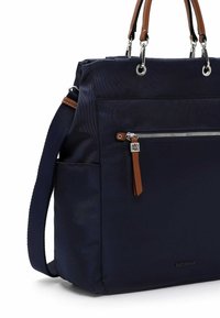 Sac à main bleu marine avec poignées en cuir marron, poche avant zippée avec tirette marron, poche latérale et bandoulière réglable.