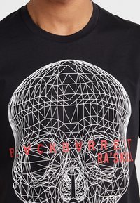 Černé bavlněné tričko s geometrickým bílým potiskem lebky a červeným textem "BLACKBARRETT RA’SKULL" pod designem.