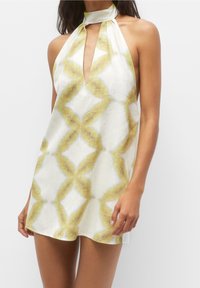 Donna che indossa un mini abito senza maniche bianco con motivo a diamante tie-dye giallo e dettaglio a chiave sul davanti.