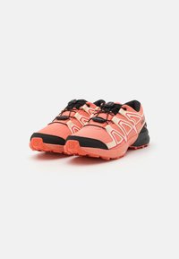 Trail running shoes in coral and black, featuring textured fabric, a rugged sole, and elastic laces for secure fit.