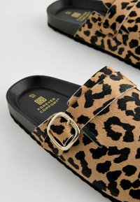 Cipele na sklizak s leopard uzorkom, s umjetnom krznenom teksturom, crnim kopčama i udobnom crnom potplatom. Imaju zlatni branding unutra.
