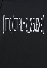 Μαύρη μπλούζα με λευκό κείμενο: "[TTC/CTRL-Z_25.EXE]" σε έντονη, σύγχρονη γραμματοσειρά, με λεία, απαλή υφή υφάσματος.