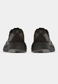 Μαύρα αθλητικά παπούτσια με υφή, παχιά σόλα και διακριτικές πράσινες λεπτομέρειες, με λείο πίσω μέρος και λογότυπο.
