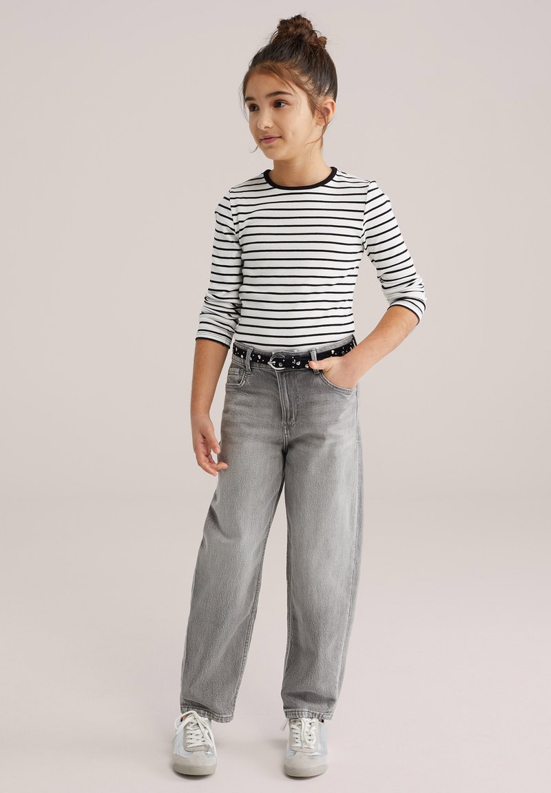 Triibuline valge ja musta pika varrukaga särk, millega on kombineeritud kõrge vöökohaga helehallid laiade säärega teksad ning valged tossud hõbedaste detailidega.