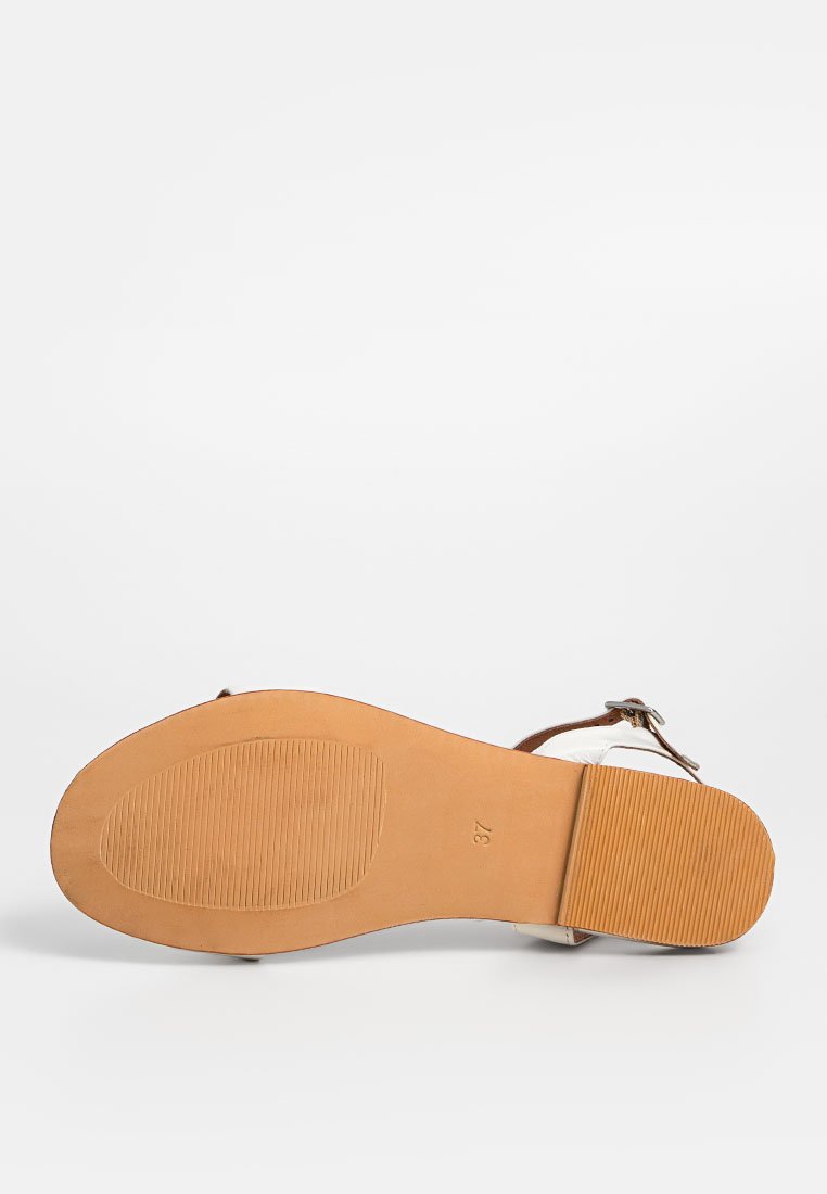 Suela de sandalía marrón con goma texturizada para mayor agarre, con una correa para el tobillo marrón y parte superior de cuero blanco. Tamaño marcado como 37.