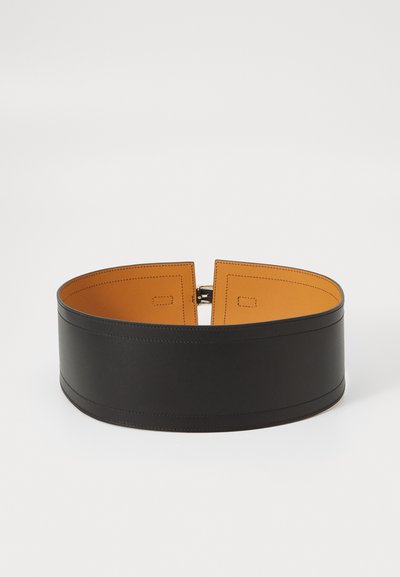 Lai musta nahkvöö, millel on sile tekstuur, kontrastne oranž siseosa ja nähtavad õmblused. Omab minimalistlikku, moodsa disaini.