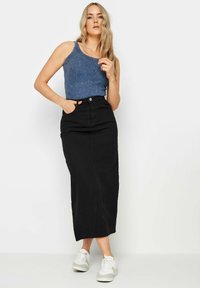 Svart denim maxikjol med rak skärning, med sidofickor. Kombination med en strukturerad blå toppen och vita sneakers.