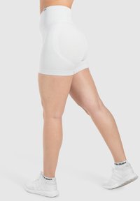 Hooggeplaatste witte shapewear shorts met een strakke pasvorm, naadloze randen en lichte stof, met een zachte textuur en subtiele accenten.