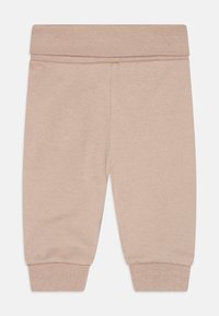 Bež pamučne trenirke s mekom teksturom, elastičnom strukom i pripijenim manžetama. Jednostavan dizajn bez uzoraka ili dodatnih dijelova.