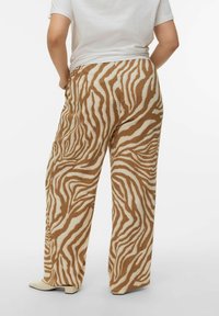 Pantalon à jambes larges avec un motif rayé zèbre en marron et crème, fabriqué en tissu texturé, avec une taille haute et une coupe décontractée.