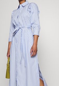 Lichtblauwe gestreepte jurk, met knopen en opgezette mouwen, tailleband en zijsplitten; gladde stof met een casual ontwerp.
