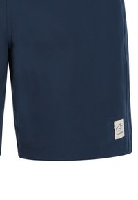 Short de bain bleu marine avec écusson logo "Protest" près de l'ourlet inférieur sur la jambe gauche.