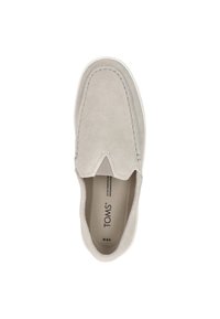 Grijze suède instapper met een ronde teen, contrasterende stiksels en een witte rubberen zool. Merknamen "TOMS" zichtbaar aan de binnenkant.