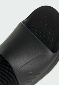 Black slide sandal with a textured rubber upper and a patterned footbed. Features a wide strap with a subtle, embossed logo detail.