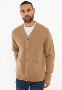 Beige gestrickte Strickjacke mit V-Ausschnitt, sechs Knöpfen, zwei Fronttaschen und gerippten Bündchen und Saum, die eine weiche Textur bietet.