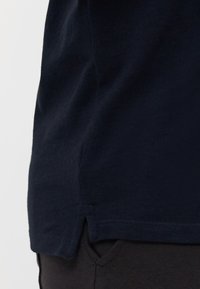 Marineblå bomull t-skjorte med en splitt på siden og flate sømmer. Stoffet ser mykt ut, med en jevn tekstur og klassisk passform.