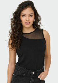 Haut sans manches noir avec un panneau en mesh transparent au niveau du cou. Le matériau est lisse, avec une coupe ajustée, accompagné d'un jean noir taille haute.