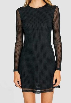 Black dress with long sheer sleeves and a dotted pattern. Knee-length, fitted design with a round neckline and textured fabric.