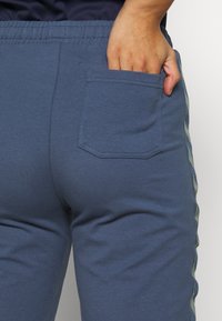 Blå bomullsbyxor med mjuk känsla, bakficka och kontrasterande sidostråk, designade för komfort med elastisk midja.