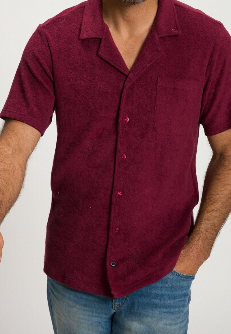 Bordowa koszula z krótkim rękawem, wykonana z teksturowanej tkaniny, z kołnierzykiem, kieszonką z przodu i kontrastowymi guzikami.
