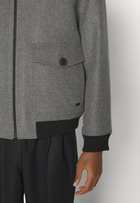 Grå ullblandad jacka med dragkedja fram, ribbade manschetter och en knappad bröstficka. Har en avslappnad passform och texturerad tyg.