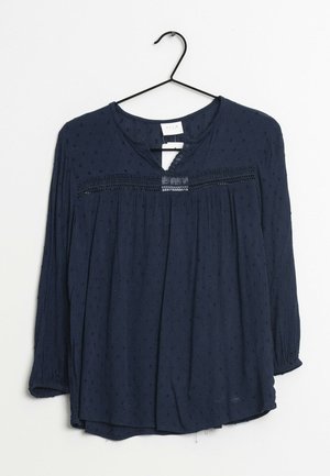 Mørkeblå bluse med lange ærmer i tekstureret stof, frontplisseringer og blondeudsmykning langs halsudskæringen. Designet med en afslappet pasform.